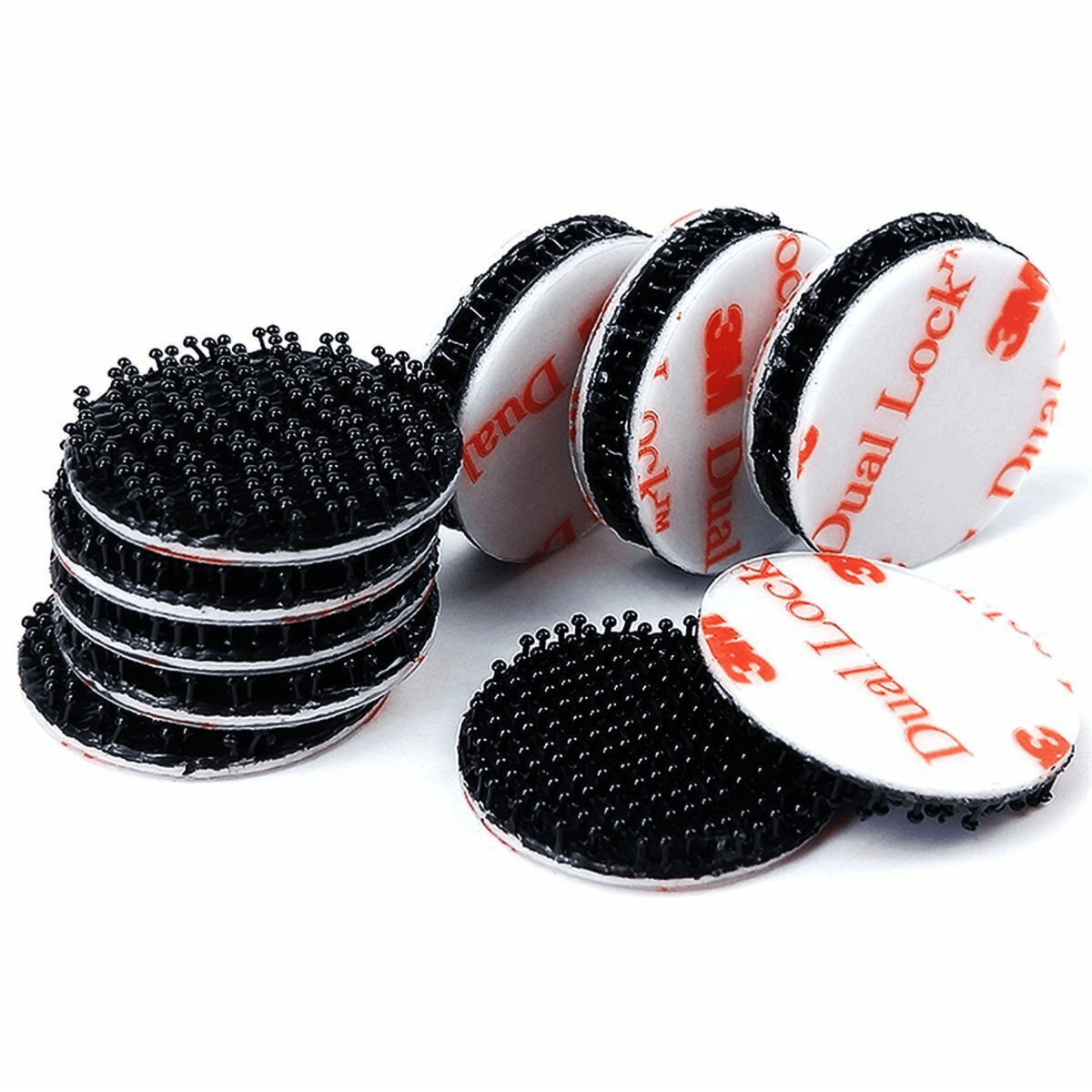 Ten black 3M Dual Lock discs, some stacked and some upright showing the white liner printed with red 3M Dual Lock logos