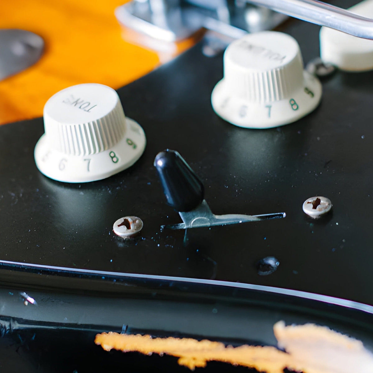 Black switch tip fitted to the pickup selector of a Strat-style guitar with black pickguard and white knobs