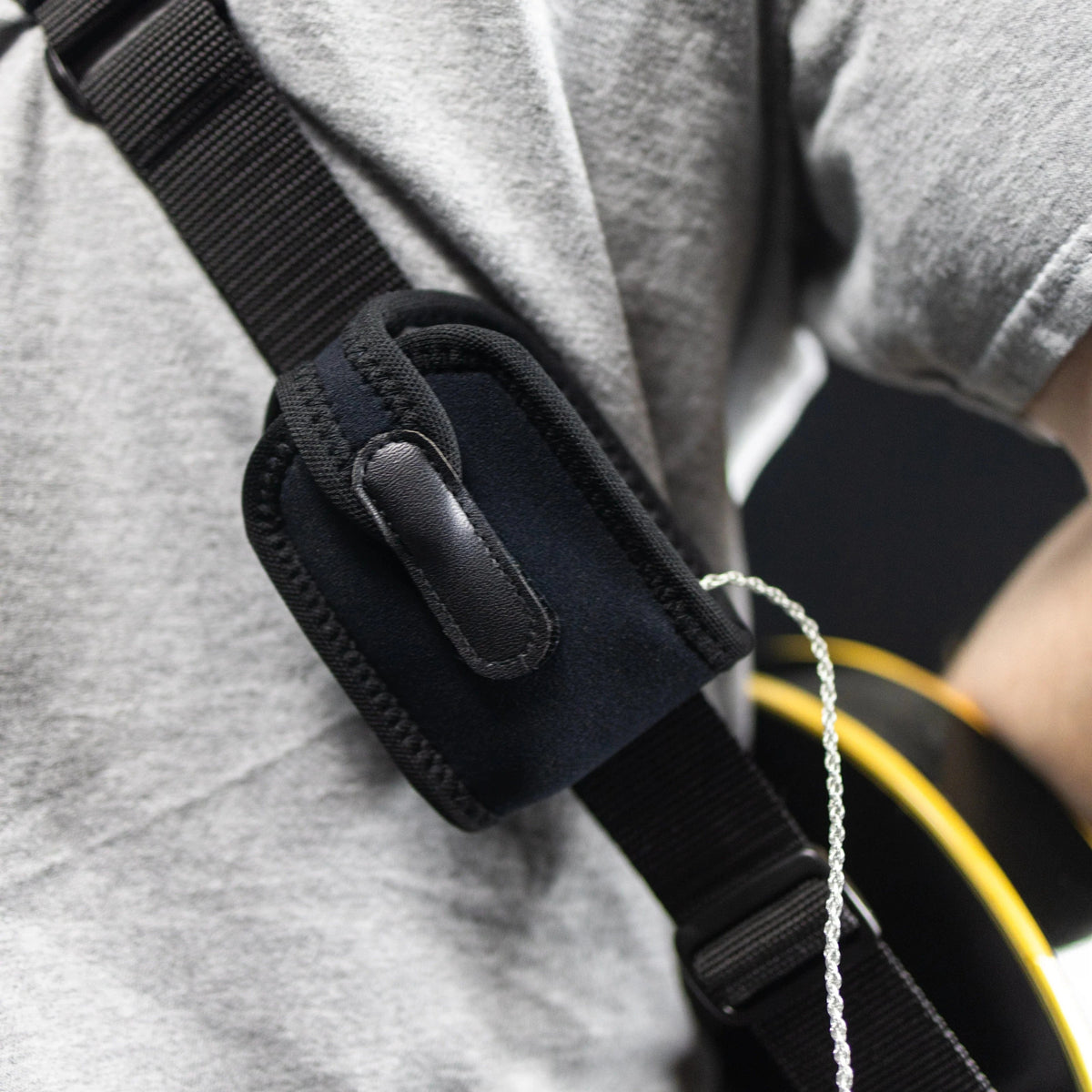 Neotech Wireless Pouch worn on a guitar strap at the shoulder, with the transmitter cable leading out of the pouch