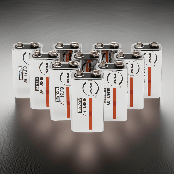 Ten NX 9V PP3 alkaline batteries arranged in rows on a dark reflective surface, labels facing forward