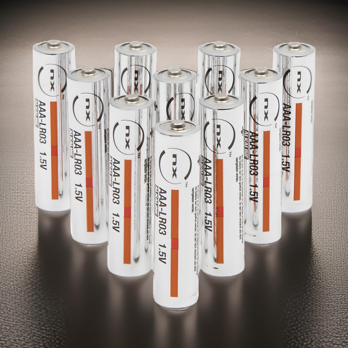 Ten NX AAA LR03 alkaline batteries arranged in rows on a dark grey background, labels facing forward