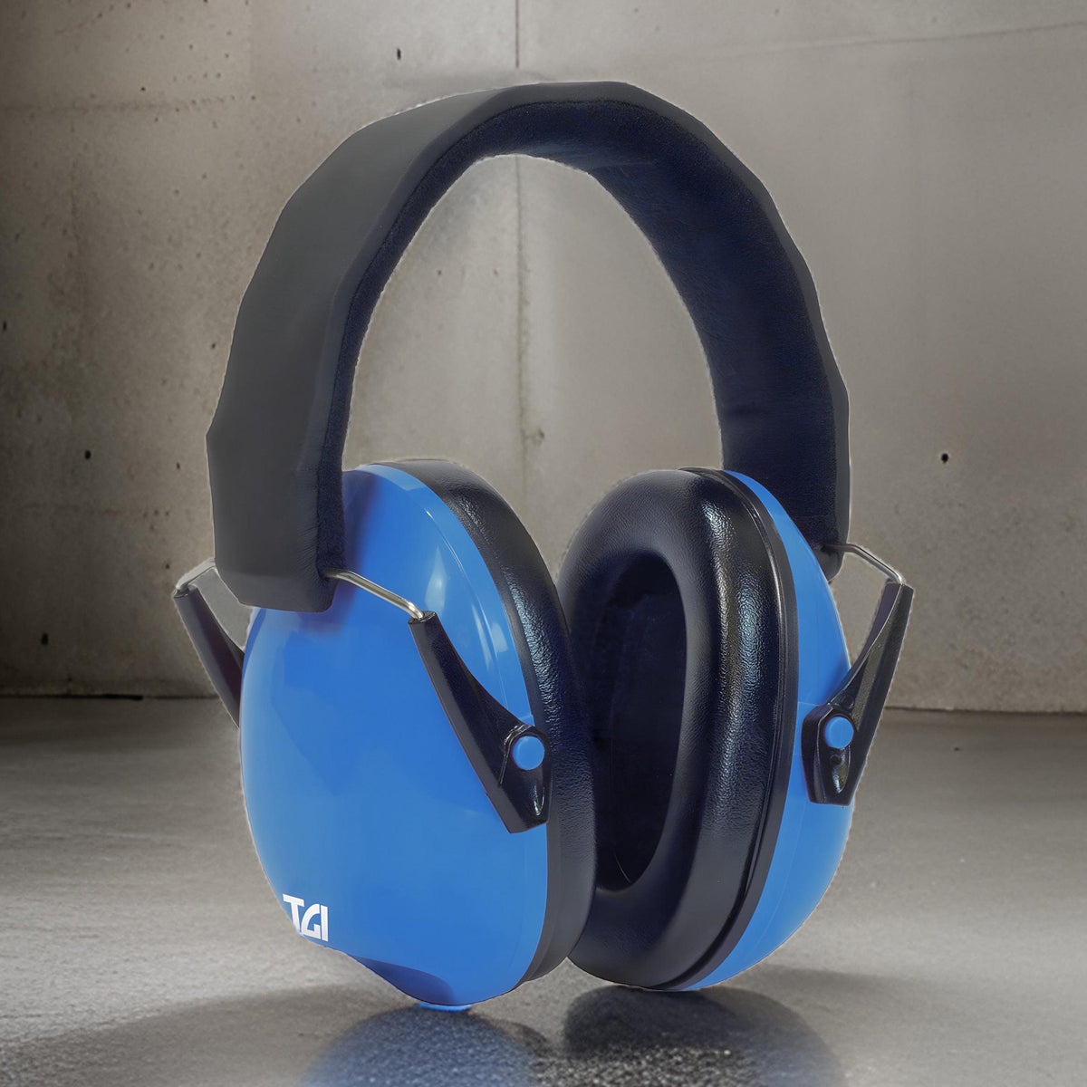 Blue TGI Junior Ear Defenders standing upright on a concrete floor