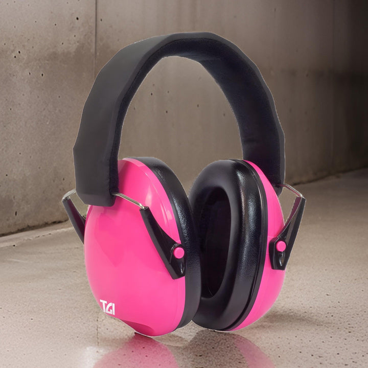 Pink TGI Junior Ear Defenders standing on a concrete floor against a concrete wall
