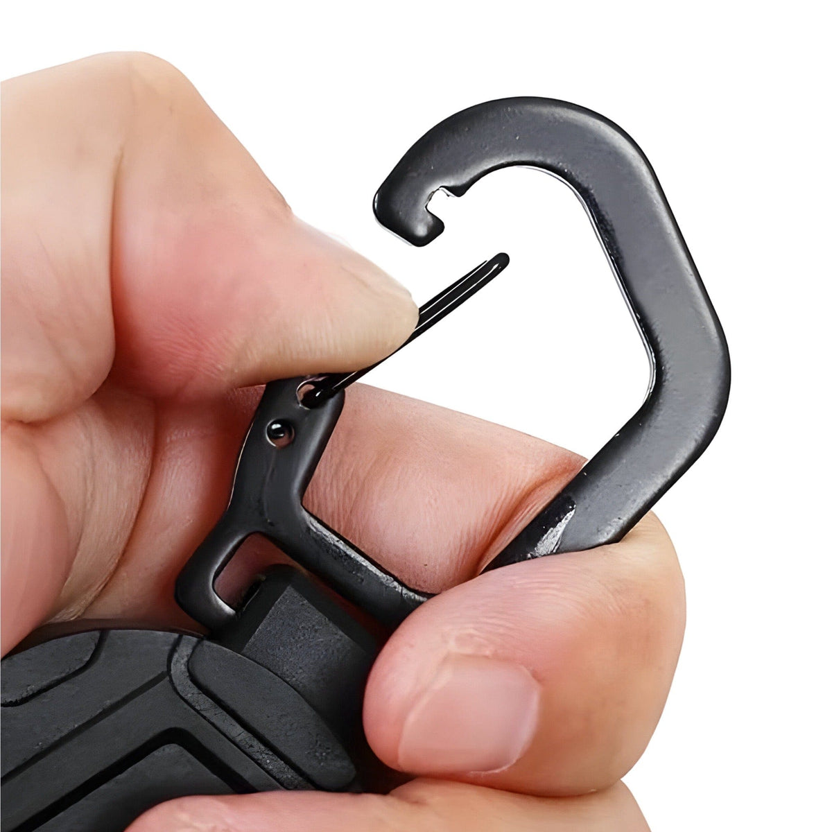 Fingers pressing open the spring gate of the black carabiner on top of the retractable reel