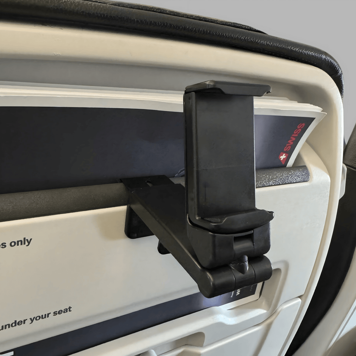 Empty phone holder clamped into an aeroplane seat-back pocket, grip set upright