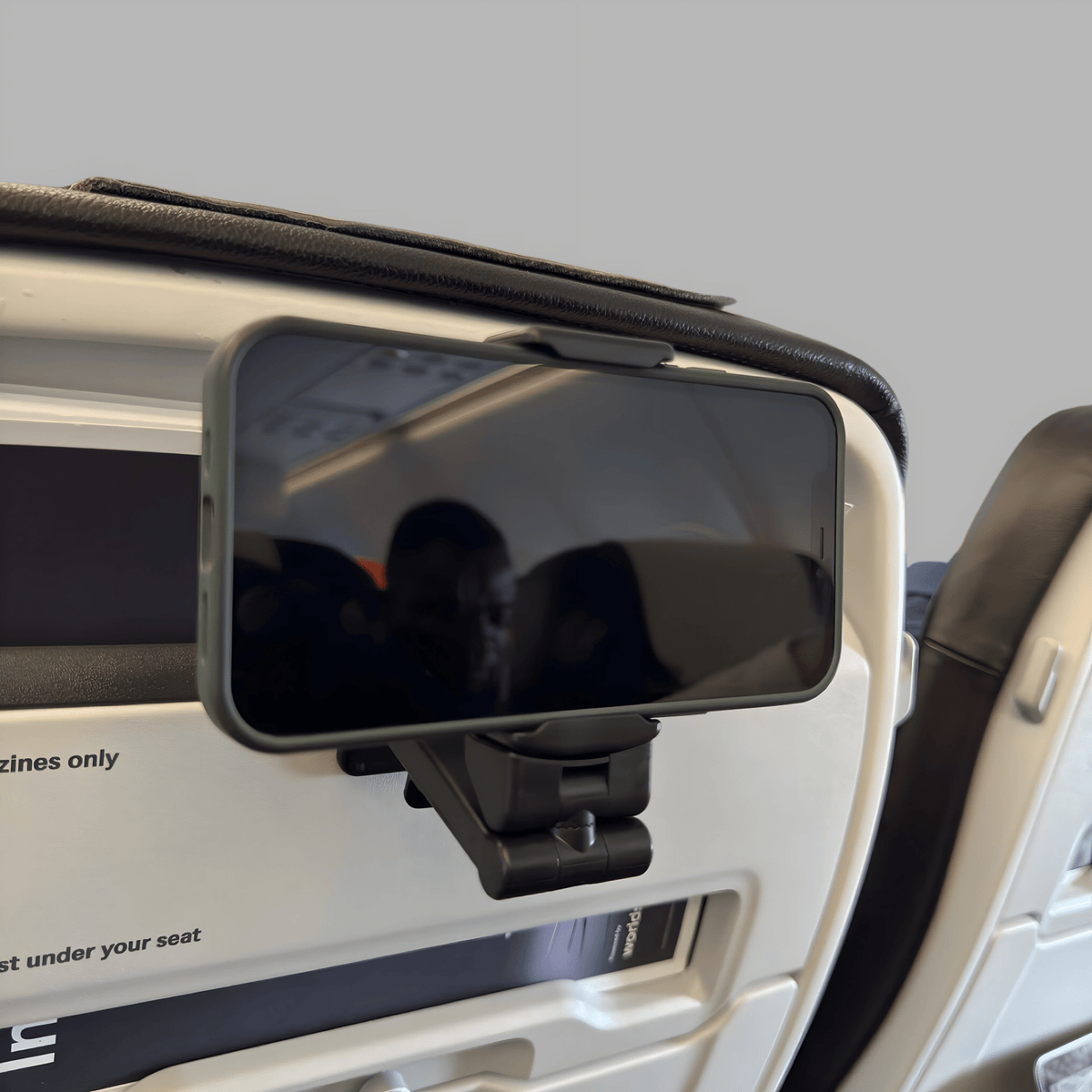 Black clamp phone holder fixed to an aeroplane seat-back, holding a phone in landscape