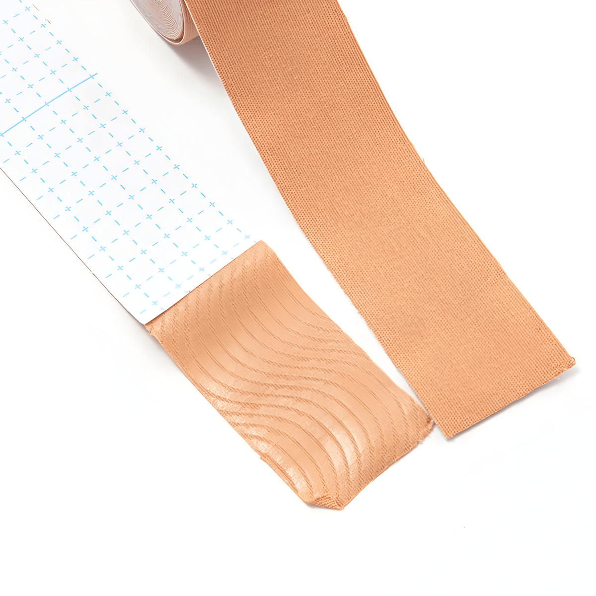 Skin tape peeled back from its grid-printed backing liner, showing the wave-pattern adhesive on the underside