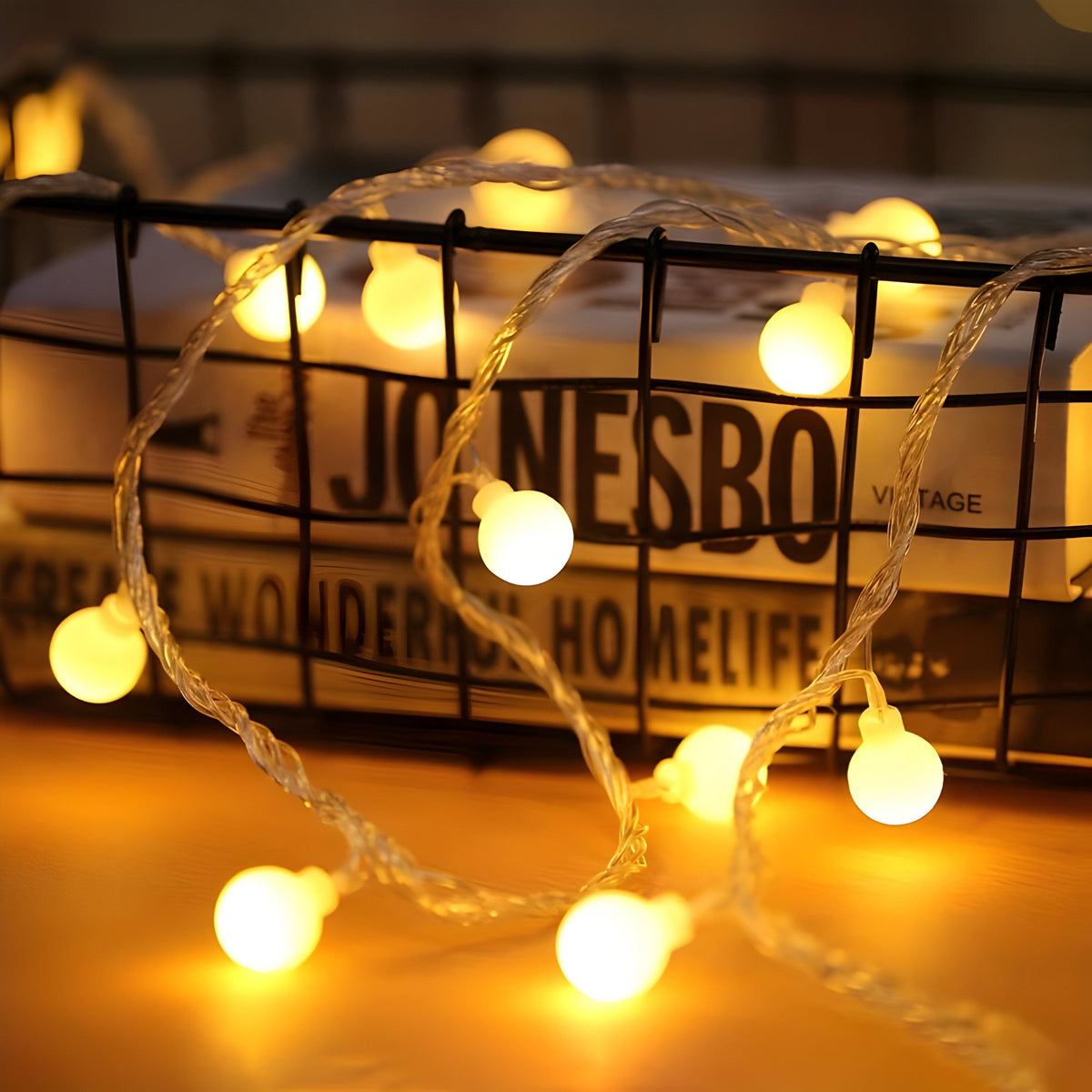Warm white USB globe string lights draped over a wire basket of books, bulbs glowing